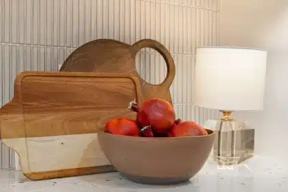 Cuisine contemporaine avec façades en bois clair, crédence en pierre continue et finitions en bronze brossé