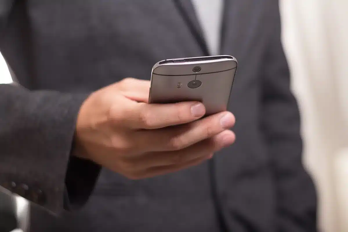 Personne tenant un smartphone affichant un flux vidéo en direct d'une caméra d'intérieur