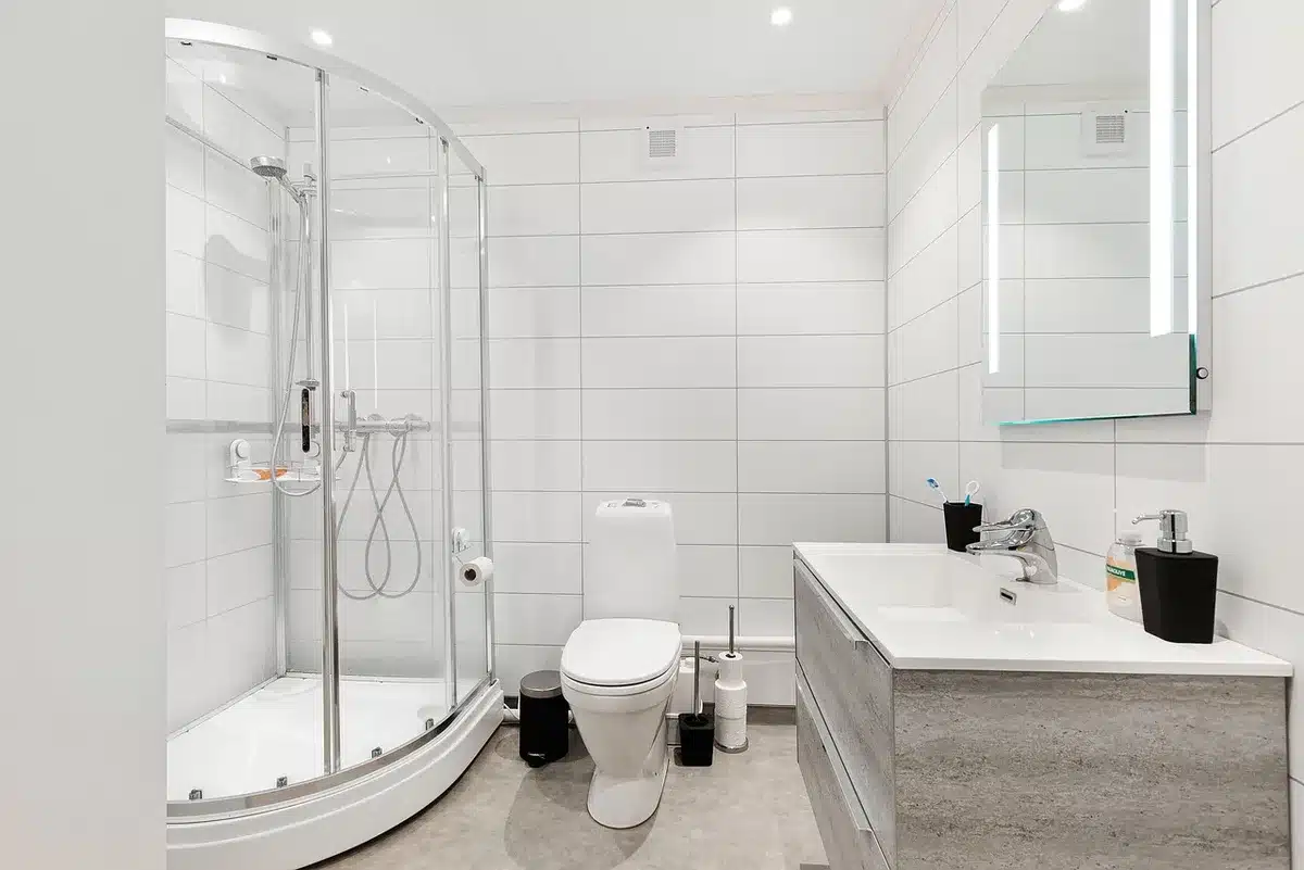 Petite salle de bain aux murs blanc cassé maximisant la lumière